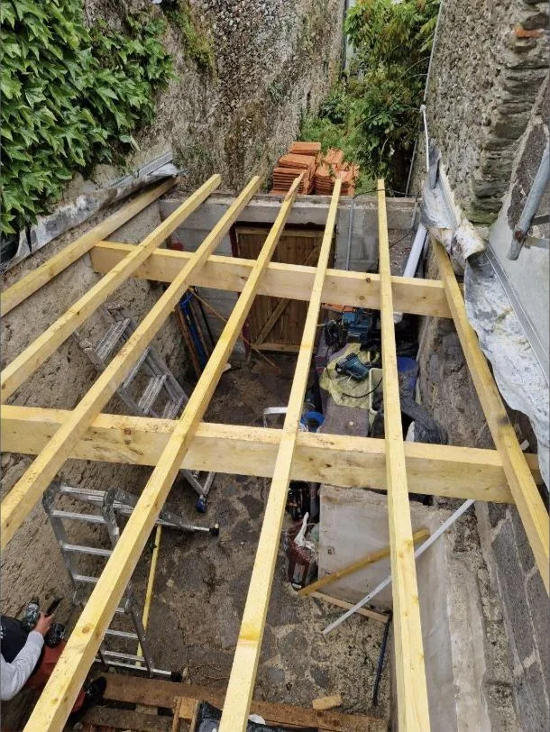 Charpente bois neuve posée sur une extension entre deux murs en pierre — chantier AC Couvreur
